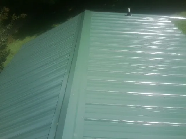 New green metal panels meeting at the ridge of a roof — Flat Roof Repair work by our crew in Ashby